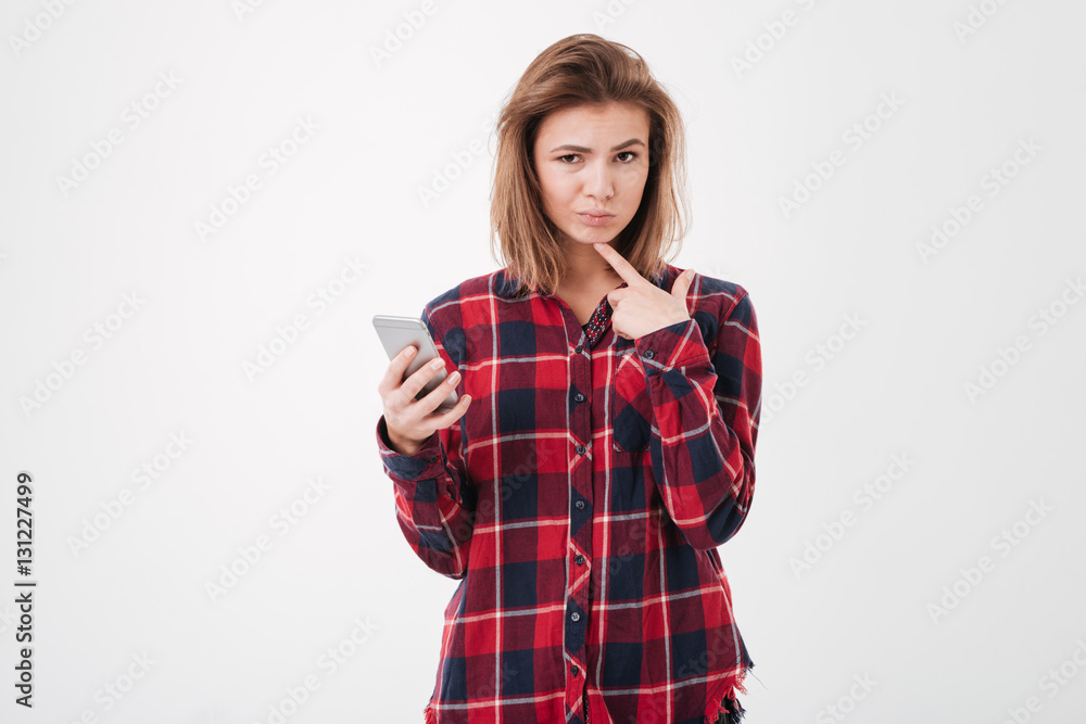 Girl in plaid shirt holding smartphone and looking at camera Girl in plaid shirt holding smartphone and looking at camera
