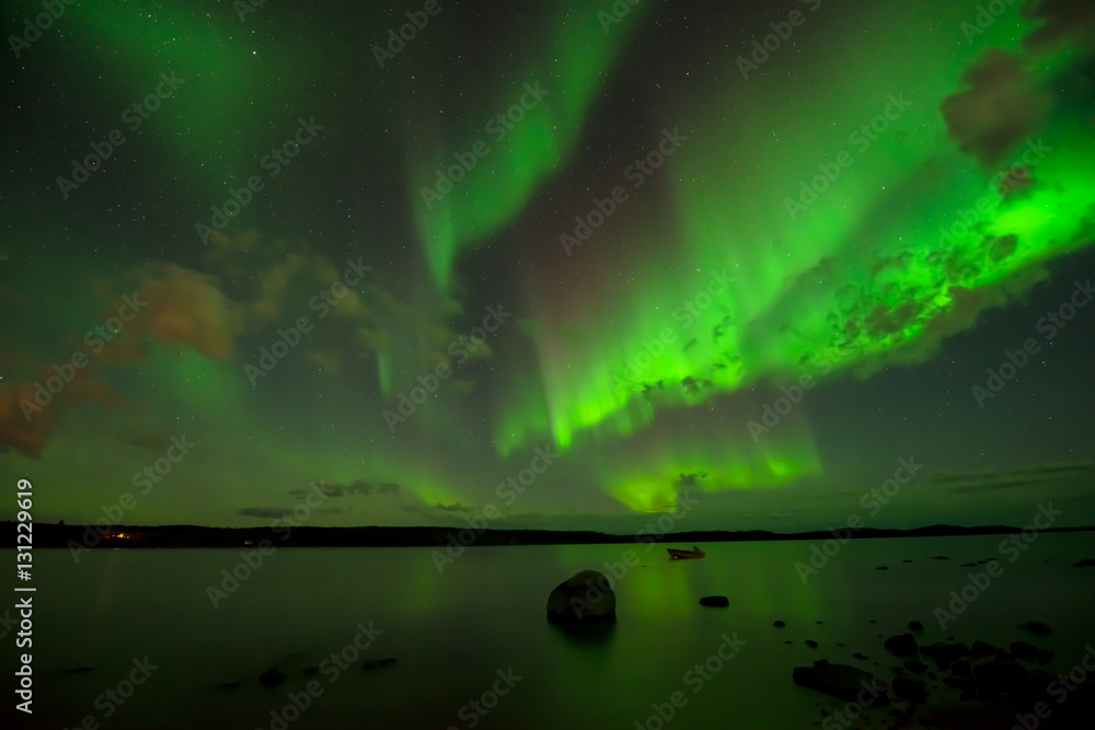 Curtains of Lights - Northern Lights drop down from starry autumn night sky over a lake.
