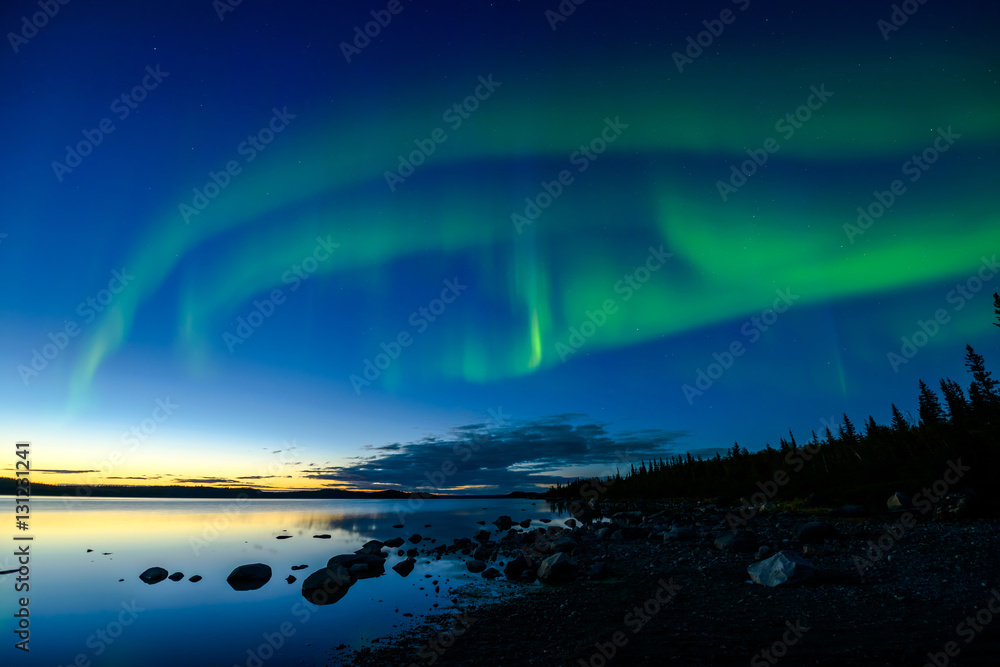 Northern Lights After Sunset - Bands of Northern Lights appear above a rocky lake right after the sun sets.