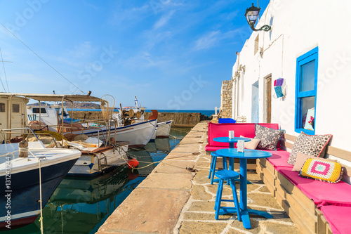 Cafe bar in Naoussa port with mooring fishing boats on Paros island, Greece