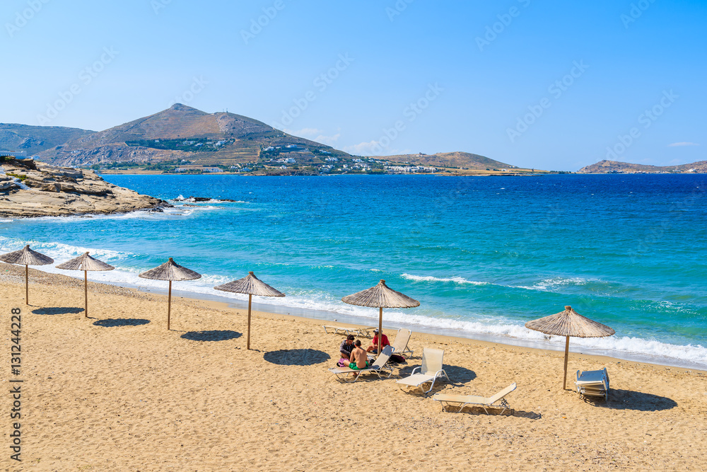 Sun umbrellas on sandy beach in Naoussa town, Paros island, Greece