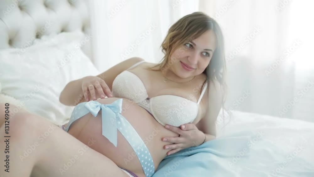 Blue ribbon on a big belly of the pregnant woman. Blue ribbon on a big belly of the pregnant woman.