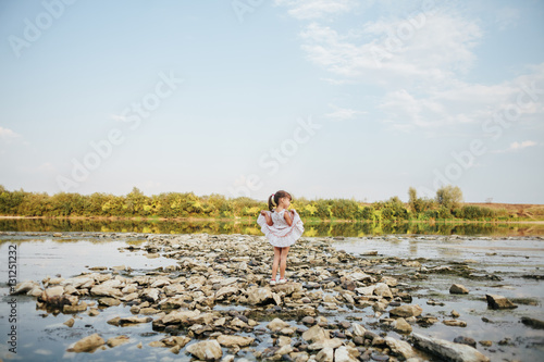 a little girl standing on stones by the river © Vladimir Matskevich