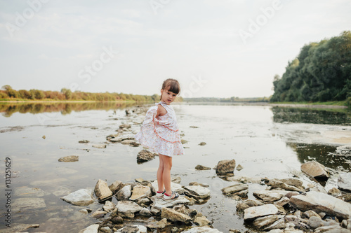 a little girl standing on stones by the river