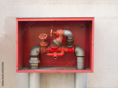 building's fire hose connections with red handles in a red box