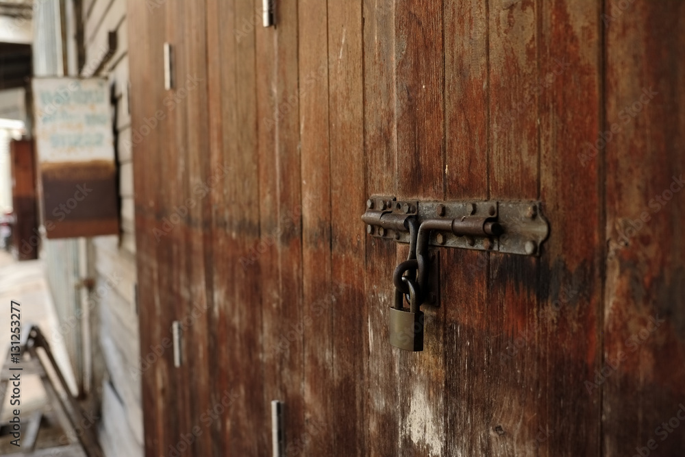 Obraz premium Old rustic metal padlock and latch on old wooden door. Film style filtered process. selective focus.