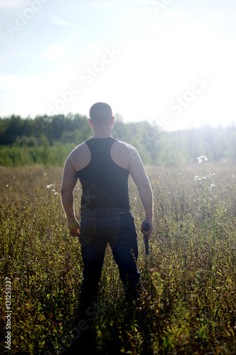 A man with a gun in his hands.Back view © lexxxx37