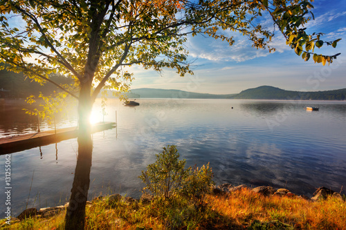 Early morning sun over shore of calm Merrymeeting Lake, New Hampshire