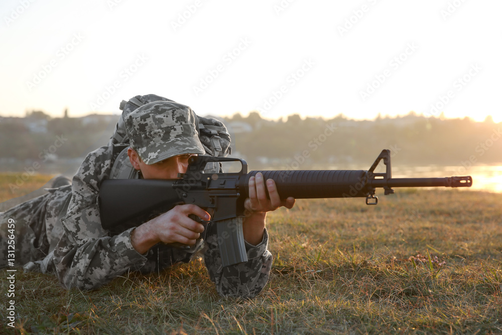 Naklejka premium Soldier in camouflage taking aim at military firing range