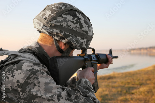 Obraz na plátně Soldier in camouflage taking aim at military firing range