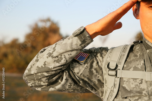 Soldier in camouflage taking salute outdoors, close up view photo