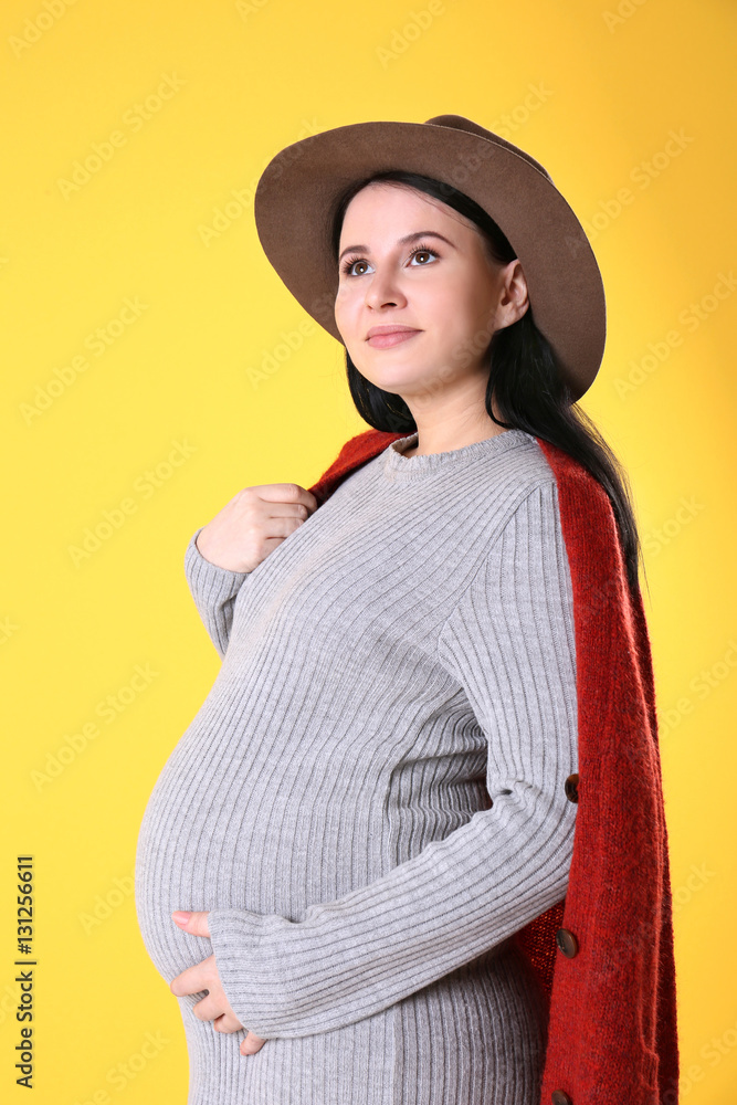 Stylish young pregnant woman in grey dress on yellow background Stylish young pregnant woman in grey dress on yellow background
