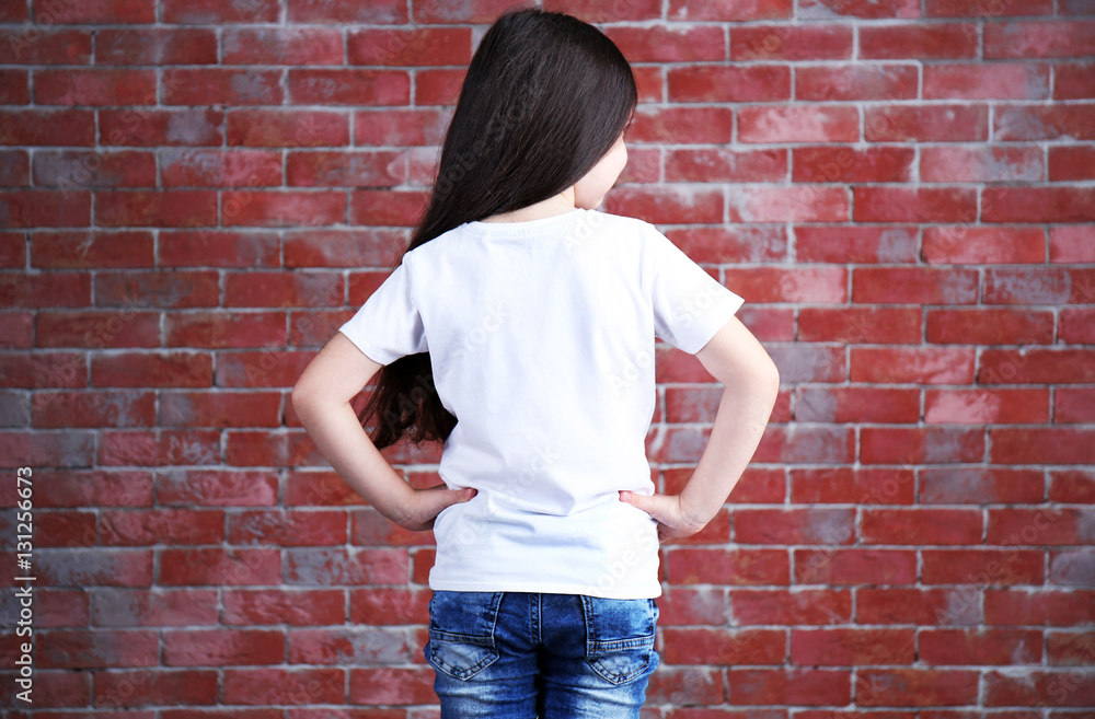 Little girl in blank white t-shirt standing against brick wall Little girl in blank white t-shirt standing against brick wall