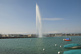 Famous Jet d'Eau fountain in Geneva Switzerland with snow capped Jura mountains in the background.