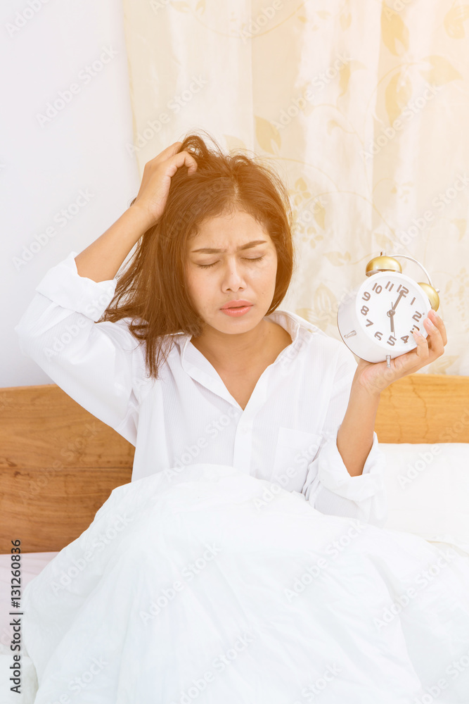 Disgruntled woman waking up in her bedroom. Disgruntled woman waking up in her bedroom.