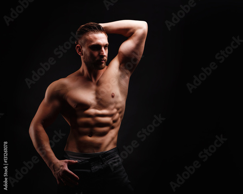 Bodybuilder posing on a black background. Dramatic portrait of an athlete. Drying. Relief and sculptural muscles of the body. Healthy lifestyles concept. Abdominal muscles and triceps.