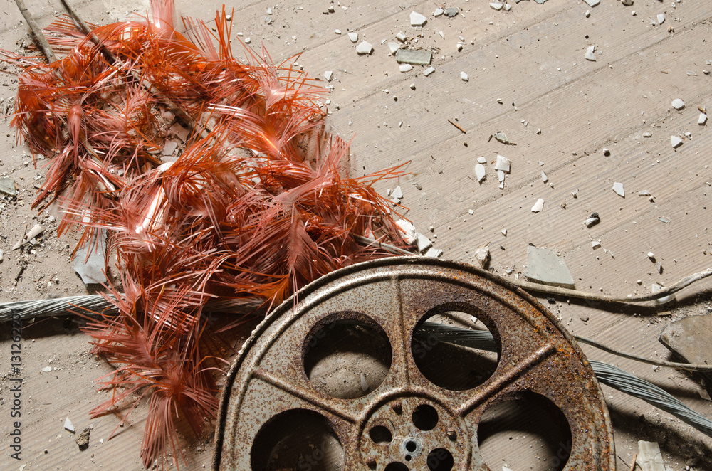 Naklejka premium An old metal rusty cinematography cinema film reel, that has been left in an abandoned cinema amongst concrete debris.