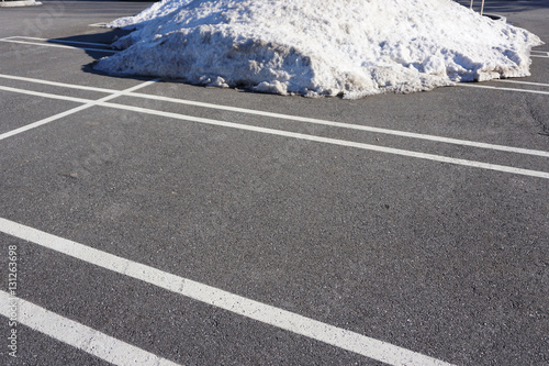 empty parking lot with snow removed and snow pile beside