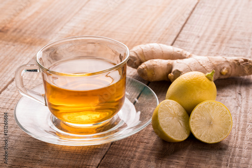 A cup of lemon ginger tea and lemon on wooden background