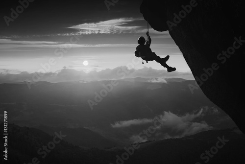 Climber against sunset background. Black and white