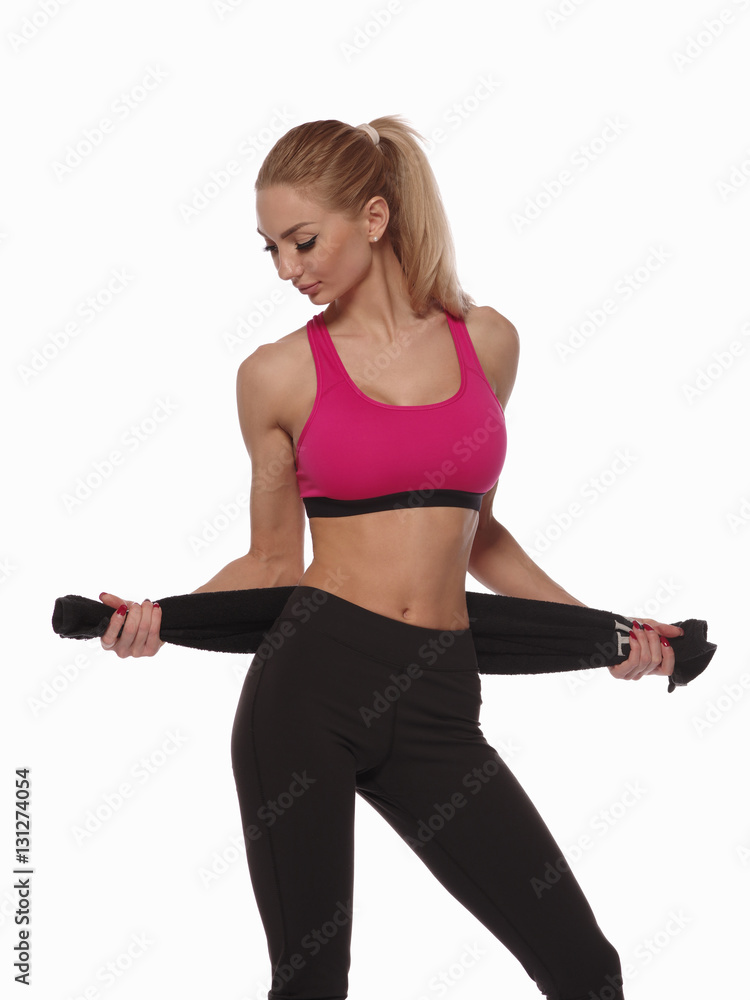 Sexy muscular young woman with perfect fitness body wearing the sport clothes is posing with a towel on the white isolated background, fitness and physical training Sexy muscular young woman with perfect fitness body wearing the sport clothes is posing with a towel on the white isolated background, fitness and physical training