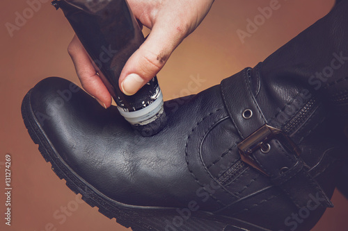 Hand with boots creme daub a leather winter boots for beauty and for protection from cold and wet.