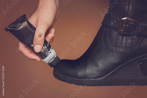 Hand with boots creme daub a leather winter boots for beauty and for protection from cold and wet.