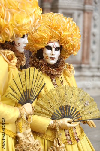 Couple masked girl in yellow dress at Venice Carnival