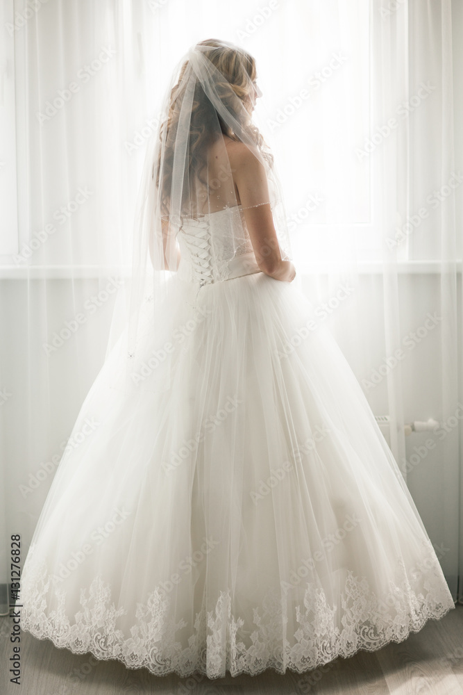 Beautiful bride in white wedding dress looking in window Beautiful bride in white wedding dress looking in window
