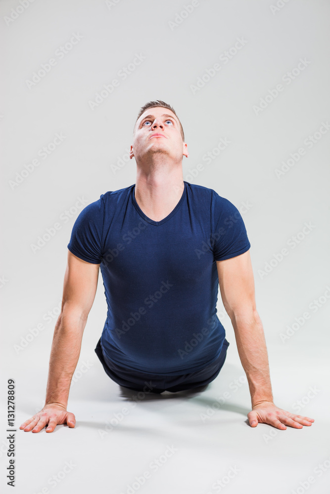 Studio shot image of young man who is stretching his body. Bhujangasana / Cobra Pose.