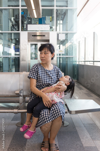 Asian Chinese mother carrying sleeping daughter inside a MRT sta photo