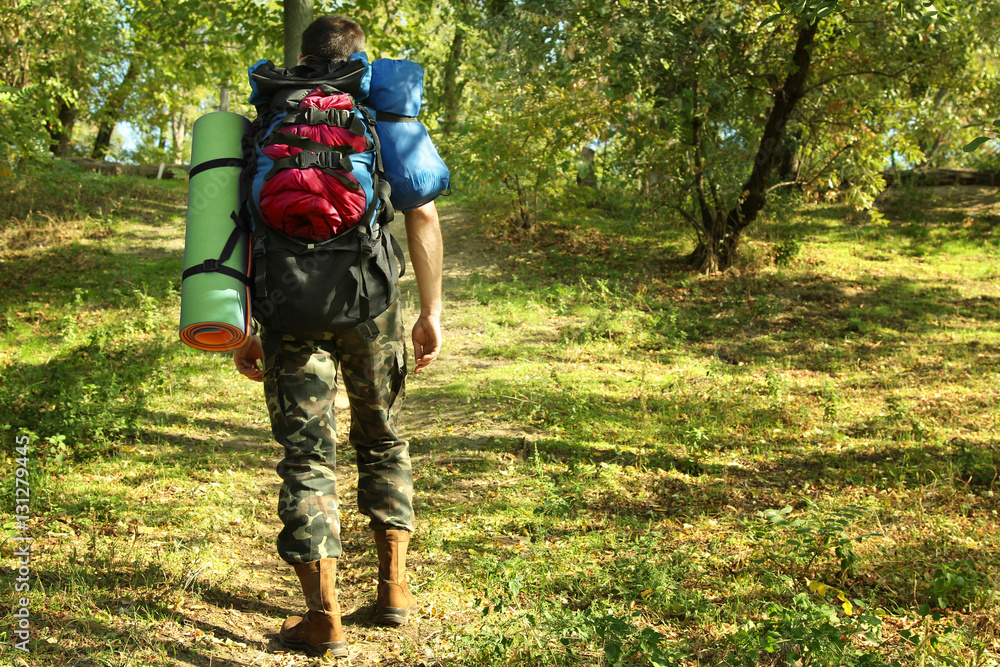 A young man travels with a backpack on his shoulders. Lifestyle travel, nature, recreation, sport.