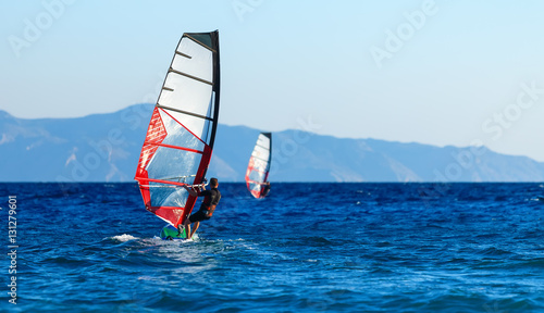 Back view of two windsurfers in action mooving parallel to each other © vladimircaribb