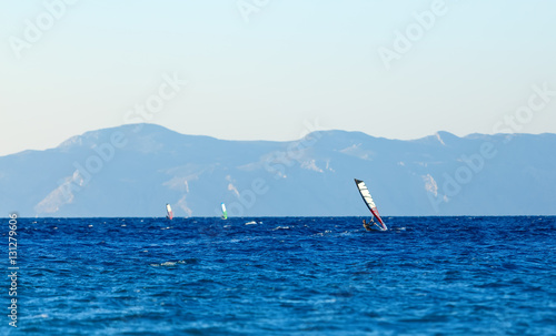 group of windsurfers on a background mountains in the Aegean sea . Greece