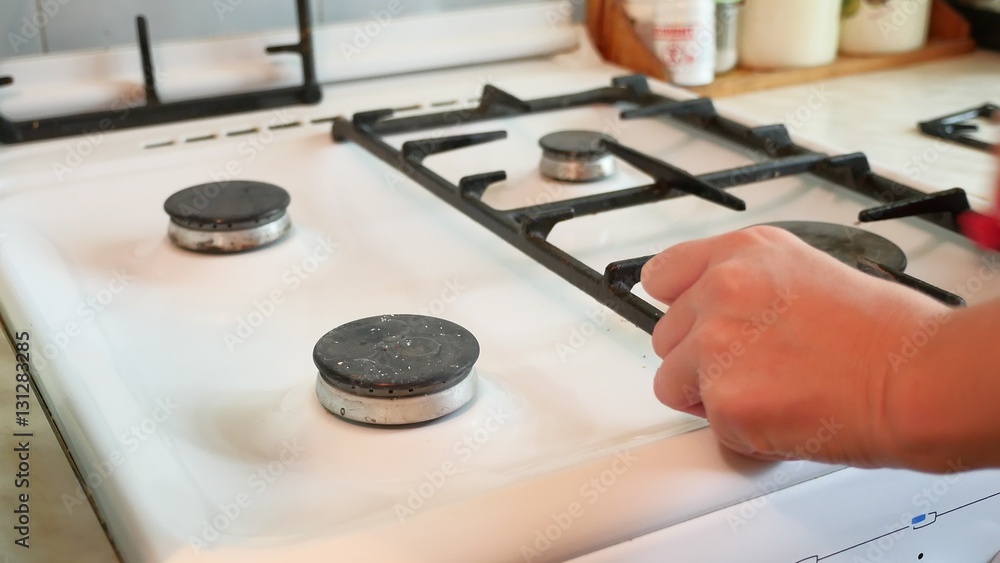 woman washes a gas stove cleaning in the kitchen woman washes a gas stove cleaning in the kitchen