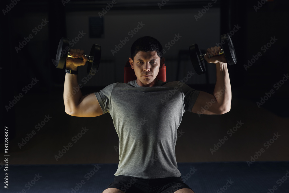 Muscular man training his shoulders with dumbbells. Muscular man training his shoulders with dumbbells.