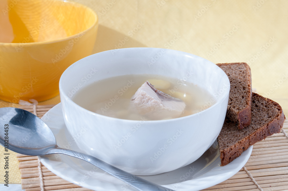 Spoon near a plate of fish soup with black bread Spoon near a plate of fish soup with black bread