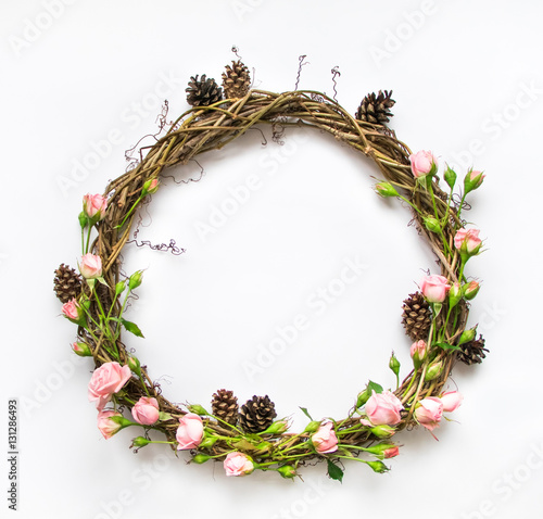 Festive wreath of vines with decorative roses, leaves and cones. Flat lay, top view