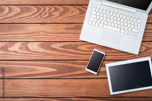 Overhead shot of white digital devices on wooden table