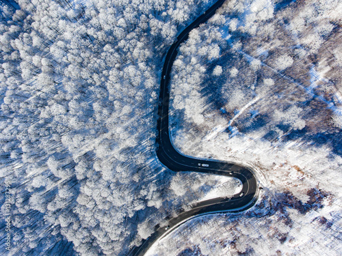 Cars on road in winter with snow covered trees aerial view