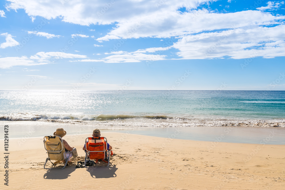 A couple relaxing on the beach at sunset A couple relaxing on the beach at sunset