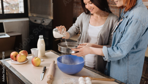 Happy looking female sieving flour