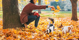 Happy young woman playing with dogs outdoors in autumn