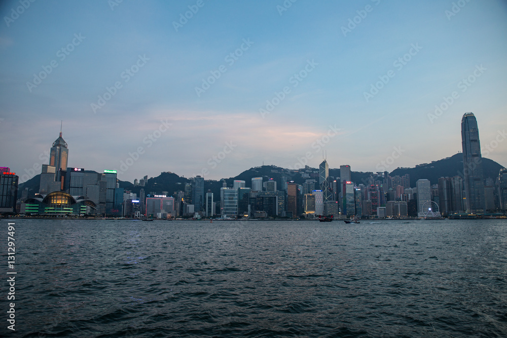 Obraz premium Hong Kong, China skyline panorama from across Victoria Harbor. Hong Kong city skyline view from harbor with skyscrapers buildings reflect in water at sunset