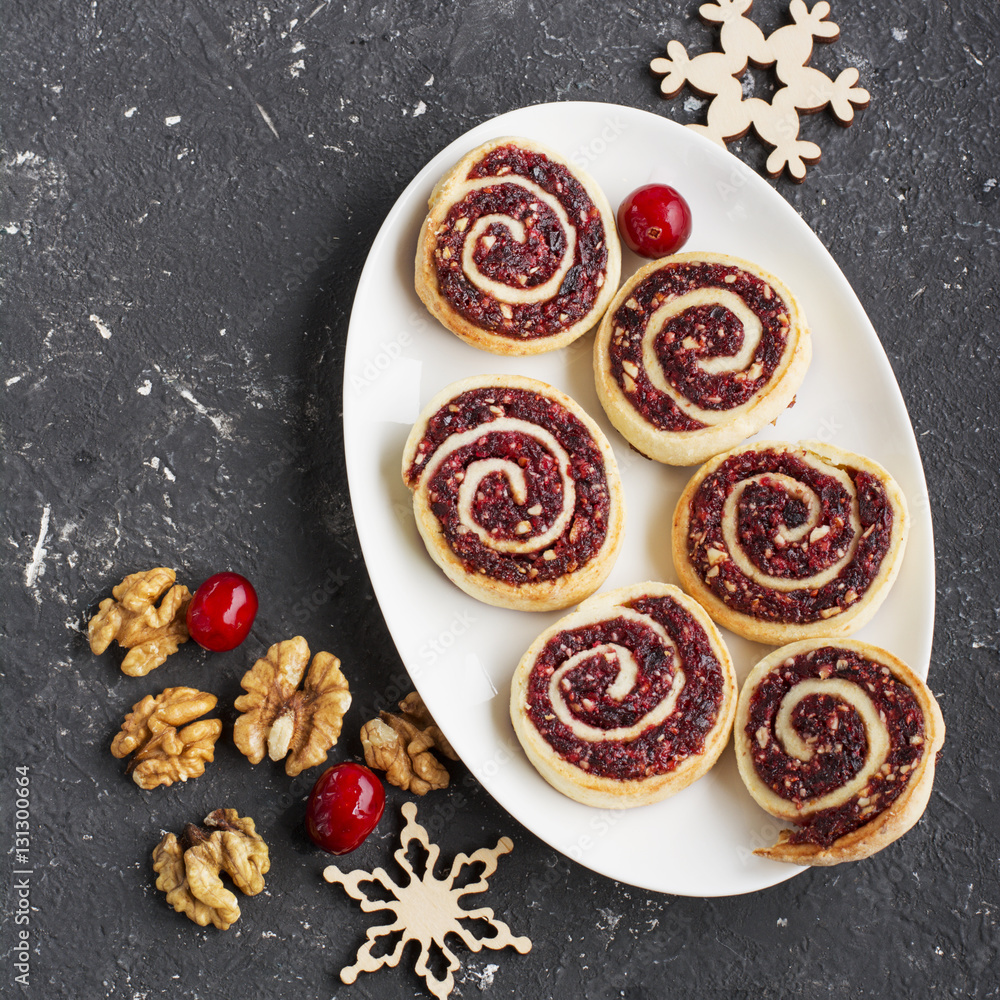 Cranberry nut swirl cookies on a white oval dish New Year's treats with nuts, cranberries, fir branches. Top view Cranberry nut swirl cookies on a white oval dish New Year's treats with nuts, cranberries, fir branches. Top view