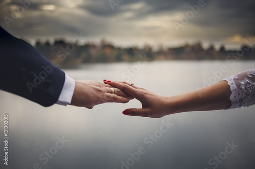 Para młoda trzyma się za ręce na tle jeziora photo