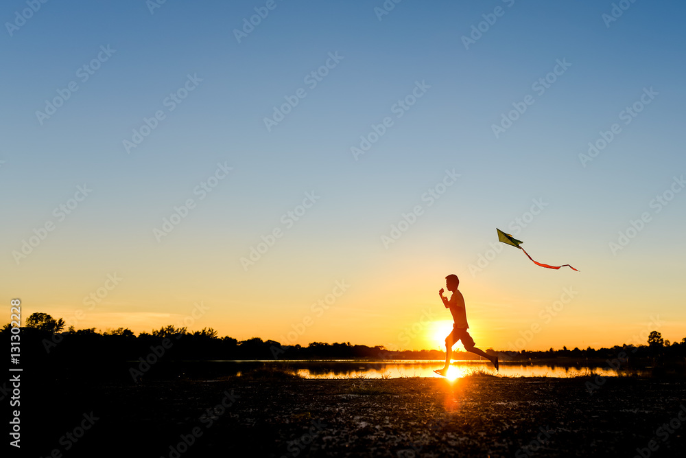 silhouette of children flying a kite at sunset
