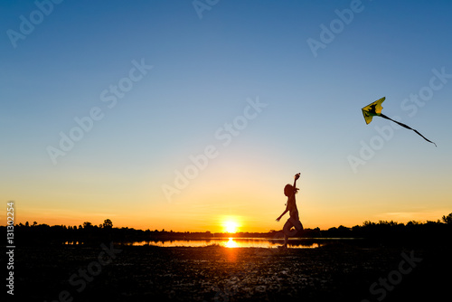 silhouette of children flying a kite at sunset © songdech17