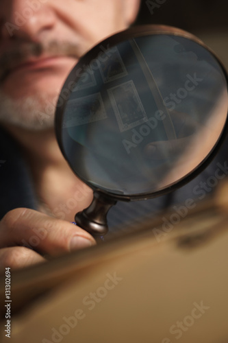 Magnifying glass with reflective stamps in the man`s hand