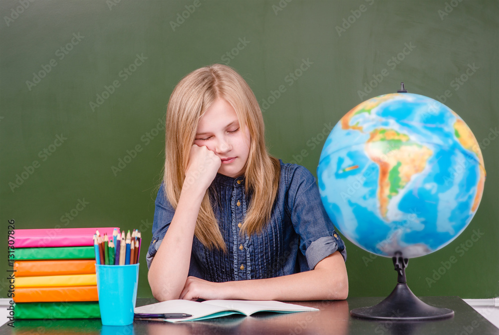 Tired girl in classroom near empty chalkboard Tired girl in classroom near empty chalkboard